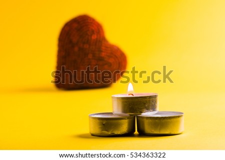 Small candles over a yellow background with a defocused heart in the background
