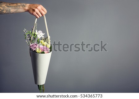 Male hand holding beautiful bouquet on dark background
