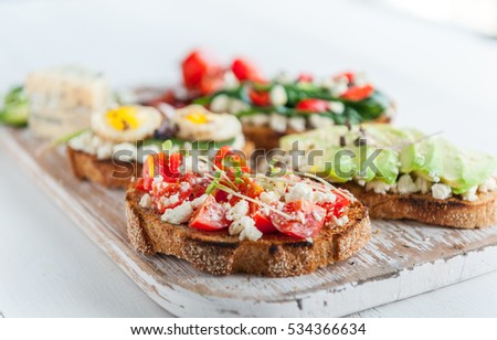 tasty and delicious bruschetta with tomatoes, spinach, feta avocado red chili pepper and blue cheese. With Micro Green and sesame seeds and flax. healthy eating concept