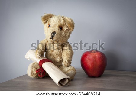 Old vintage teddy-bear with apple sitting on the cupboard
