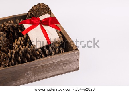 Christmas gift tied with red ribbon and pine cone isolated on white background