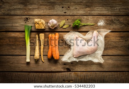 Cooking - chicken stock (bouillon, soup) recipe ingredients on rustic wooden background. Poultry and root vegetables -  rural kitchen scenery captured from above (top view, flat lay).