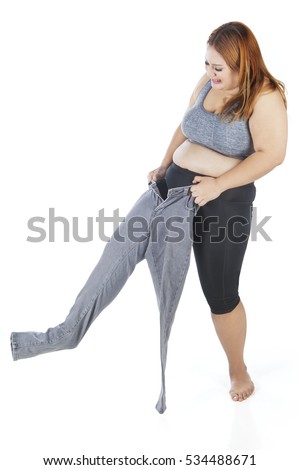 Picture of overweight young woman wearing old jeans, isolated on white background