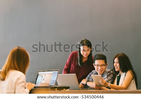 Group of young Asian business colleagues in team casual discussion, startup project business meeting or happy teamwork brainstorm concept, with copy space, depth of field effect