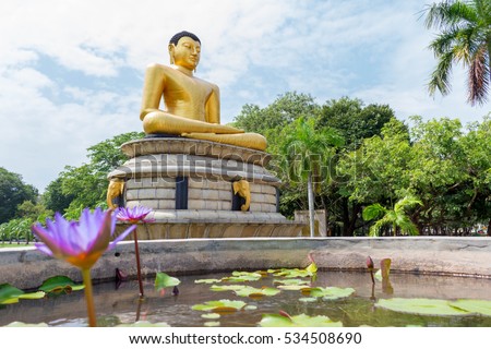 statue budha in colombo shri-lanka in park with reflection in pool fountain blue sky palm 
lotus