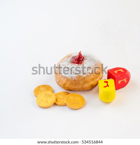 Fresh donut with jelly, chocolate coins and wood dreidels  for Hanukkah celebration. 