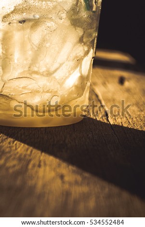 Glass with ice condensation in golden sunlight.