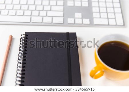 Office desktop with notebook, pencil, coffee and computer keyboard