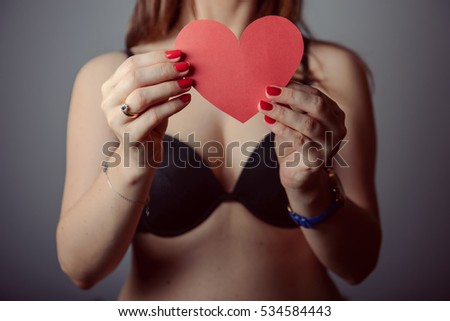 Woman holding big red heart on gray background