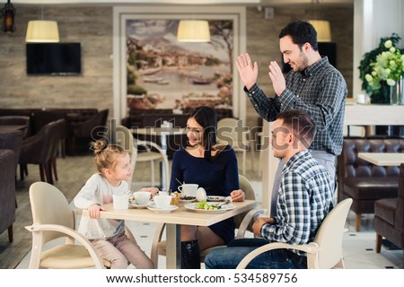 family, parenthood, technology, people concept - happy mother, father and little girl having dinner asked waiter to take picture by smartphone