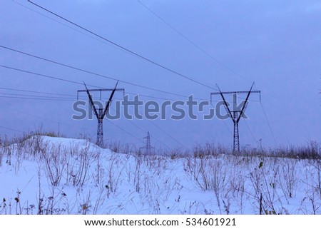 High-voltage power line in the late evening in the forest littered with snow