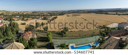 Panoramic views from Loarre Aragon Huesca Spain, wheat fields already harvested, municipal swimming pool, dome of the church of San Esteban, access road to the village, in background Navas reservoir