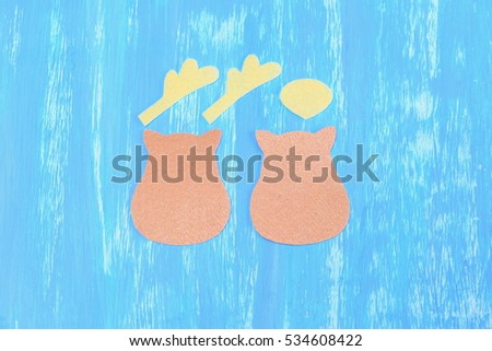 Sewing Christmas reindeer decoration of felt. Step. Beige and yellow felt pieces cut in the shape of a deer head isolated on blue wooden background. Christmas simple DIY instruction for kids. Top view