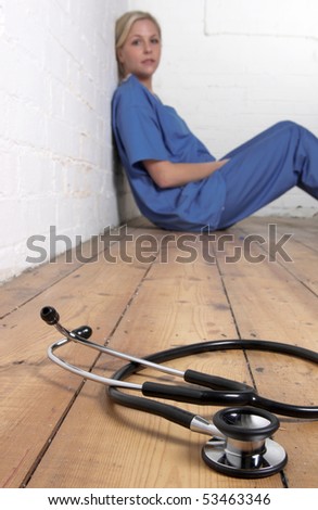 Nurse sitting on the floor with a stethoscope n the foreground