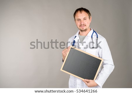 male doctor with stethoscope holding a plate of black color, ideal for writing medical subjects advertising