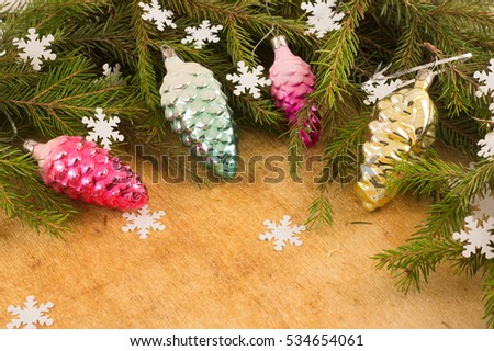 The branches of Christmas trees and  fallal cone decorations on the background of wooden boards and snowflakes. Christmas and New Year's background.