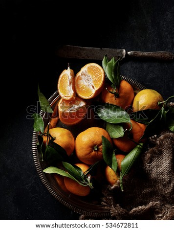 Some ripe tangerines with leaves on dark background