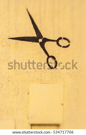 Black scissors graffiti painting on yellow wall, copy space for adding custom text