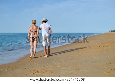 Back view of couple on holiday travel vacation beach. Business man talking using mobile phone. Blue sunny ocean sky background