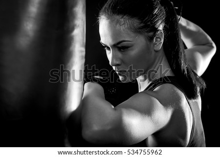Studio shot of female boxer punching a boxing bag with elbow, Black and white.
