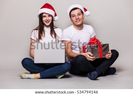 Christmas couple with laptop and gift on grey background