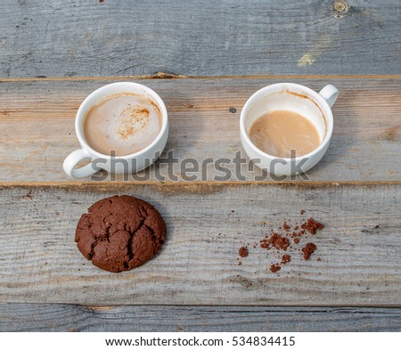 A cup of coffee, the cup is empty. Chocolate cookies, crumbs from cookies. An empty cup and a full cup. Old wooden table, rustic style.