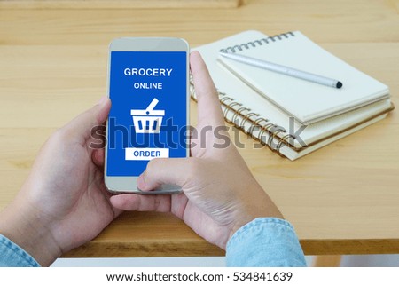 Hand holding blank screen device smart phone on wood table background, technology, mock up