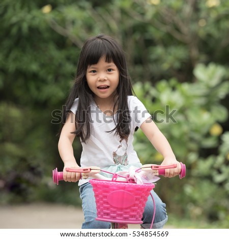 A little cute girl rides a bicycle down the street