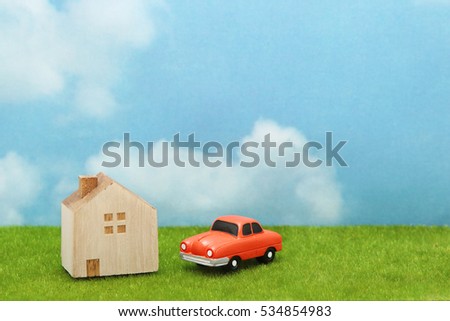 House and car on green grass over blue sky and clouds. My home and car concept.