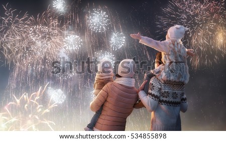 New Year holiday. Happy family, parents and daughters children girls are watching fireworks. The child sits on the shoulders of his father on snowy winter walk in nature. Holidays winter season. Royalty-Free Stock Photo #534855898