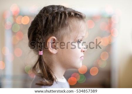 Portrait of a little girl with pigtails in profile against a background bokeh