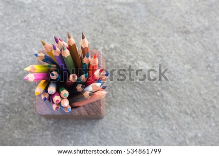 color pencils in a wood cup on concrete floor