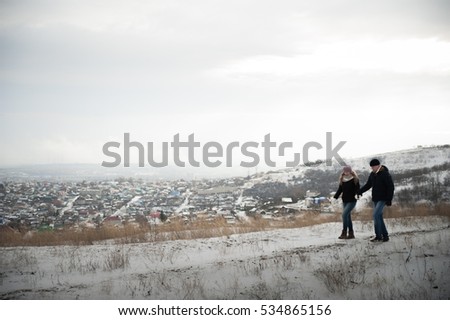 Lovers walk in the winter on the mountain on the background of the city. Couple in love running around in the snow forest. Winter Love Story. walking and running around in the winter. 