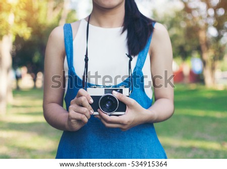 vintage autumn photo with girl standing in a park with old camera.