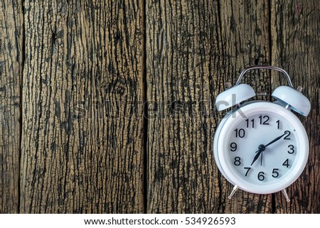 White alarm clock with bells on old wooden floor