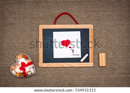 Love concept. Valentines love card with red hearts on linen background. Black board hand drawn picture of little man in love with hearts. Sweet candies in a transparent box heart shaped. Rustic youth.
