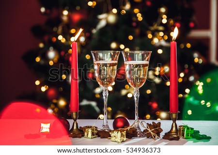 Christmas still life - Two Stemware of champagne with Xmas decorations and Christmas tree on blurred red background