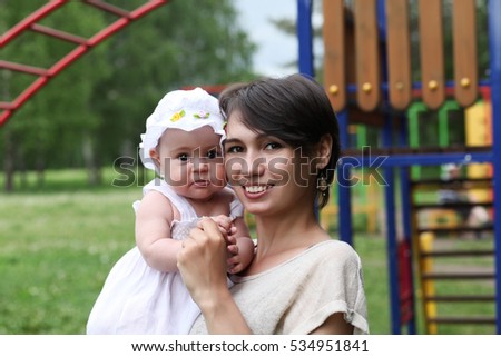 Happy young mother walks in the park with her little daughter.