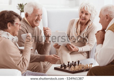 Happy pensioners of rest home playing chess Royalty-Free Stock Photo #534961387