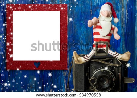Christmas photo frame  backgrounds, vintage ragdoll Santa Claus over old photographic camera, blue wooden background with copy space