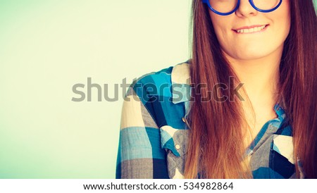 Studying, education and fun concept. Nerdy woman in weird big glasses. Studio shot on blue background