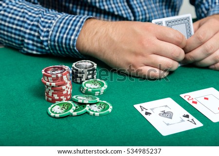 chips and cards for poker in hand on green table

