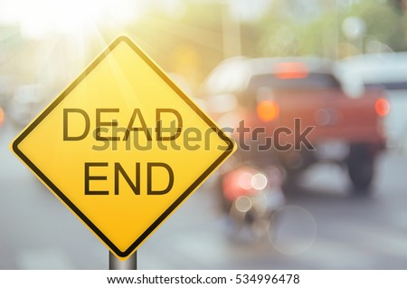 Dead end warning sign on blur traffic road with colorful bokeh light abstract background. Copy space of transportation and travel concept. Retro tone filter color style. 