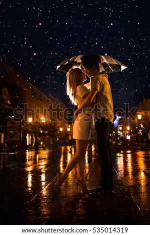 Love in the rain / Silhouette of kissing couple under umbrella