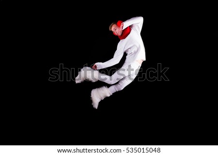 Guy gymnast dressed as christmas elf flying without visible ropes isolated on black background