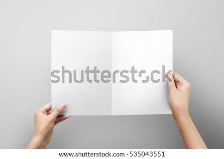 Hands holding paper blank a4 size for letter paper on grey  background. Royalty-Free Stock Photo #535043551