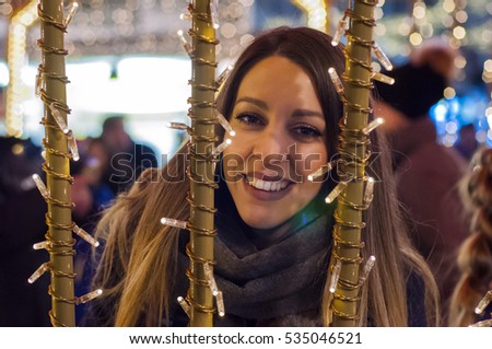 Happy woman Feeling the urban christmas vibe at night. Happy woman looking up with christmas light at night