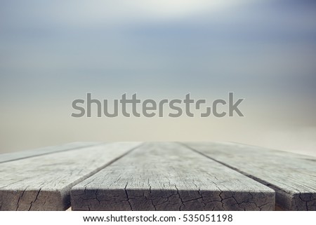 Wood table top on blurred blue sea background - used for display or montage your products. Vintage effect filter style pictures