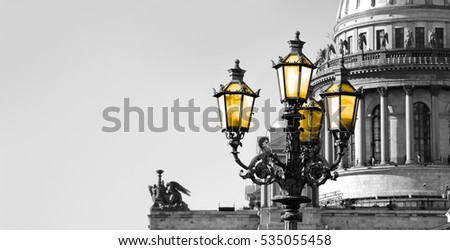 Black and white view of Saint Petersburg with vintage street lamp with yellow light.
Saint Isaac Cathedral in retro tone. Black and white photo with color 

