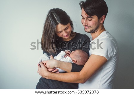 Woman and man holding a newborn. Mom, dad and baby. Close-up. Royalty-Free Stock Photo #535072078